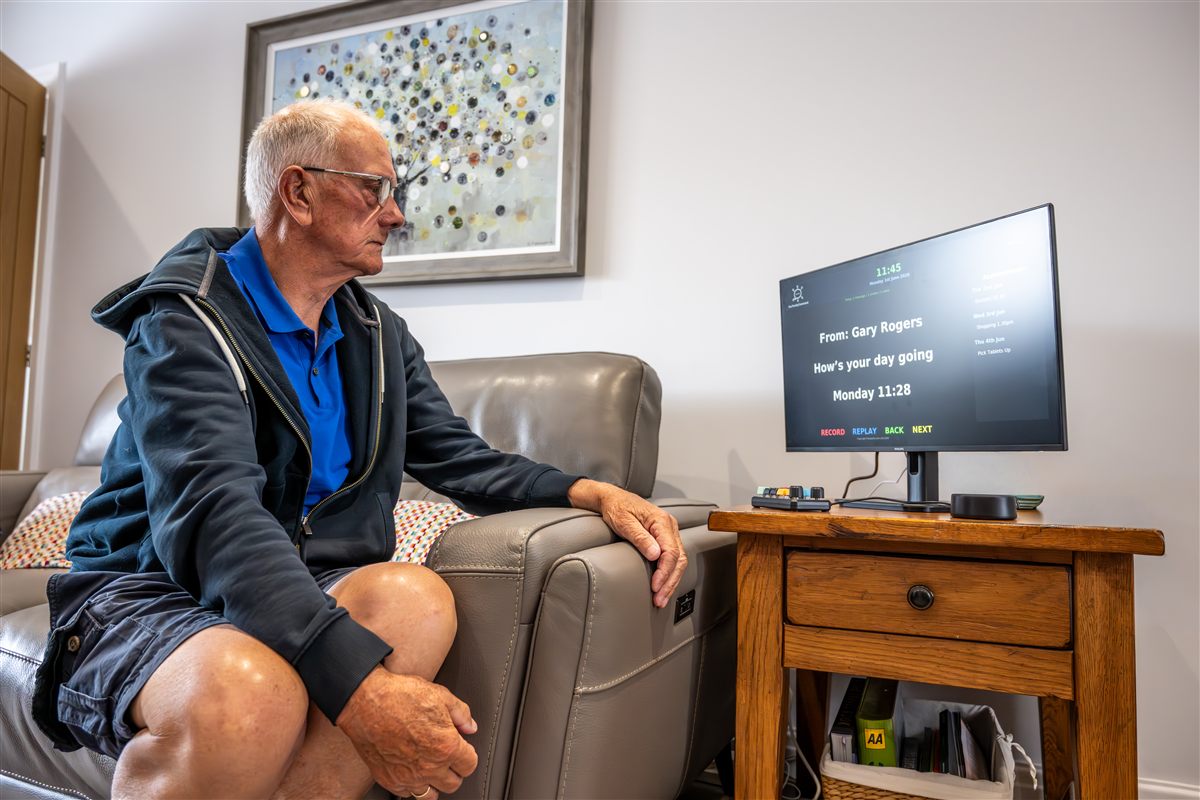 Elderly man relaxing in his chair with OurFamilyConnected beside him